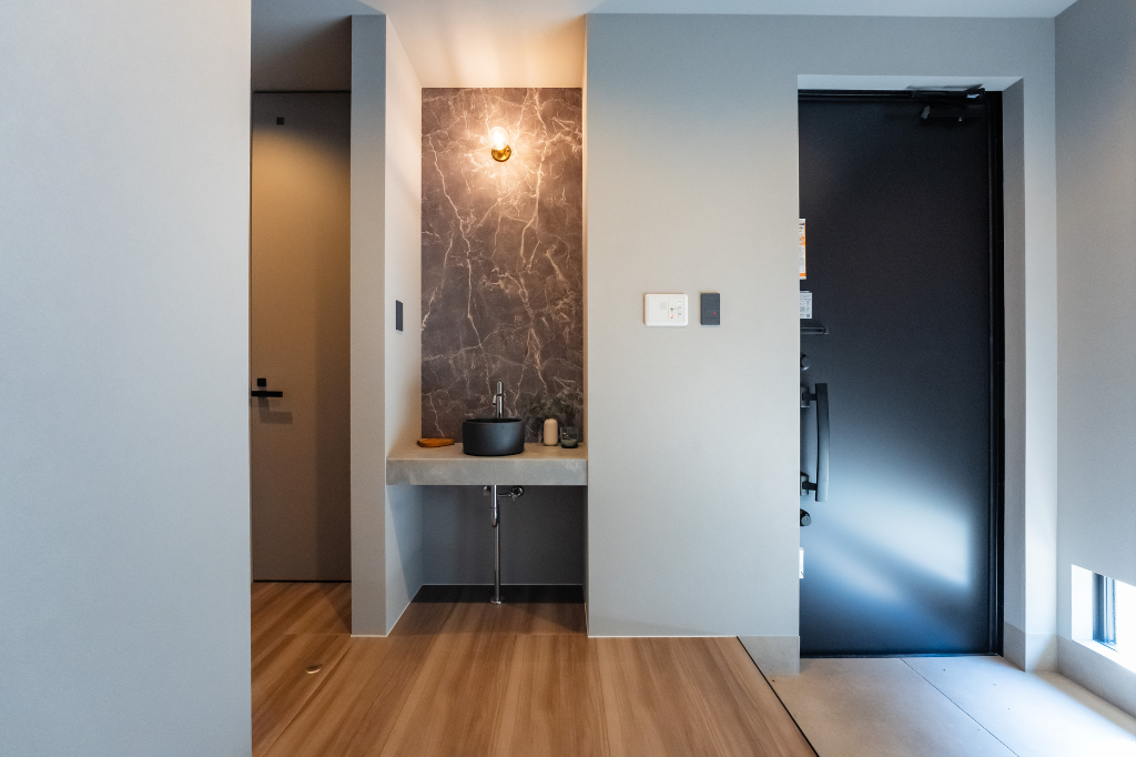 壁を凹ませる設計で、タイル風の壁紙を本物のタイルのように見せている玄関手洗い